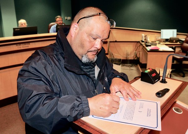 Newly appointed councilmember, John Garza, signs his papers Tuesday night. 